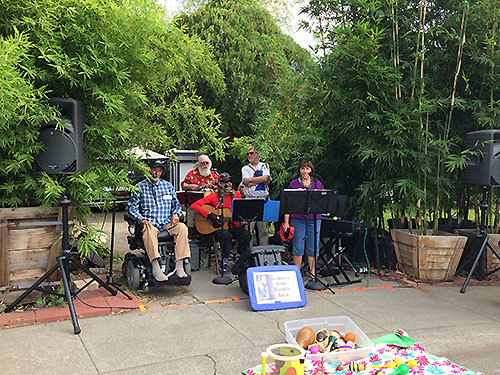 A second band performs while community members paint the street mural.